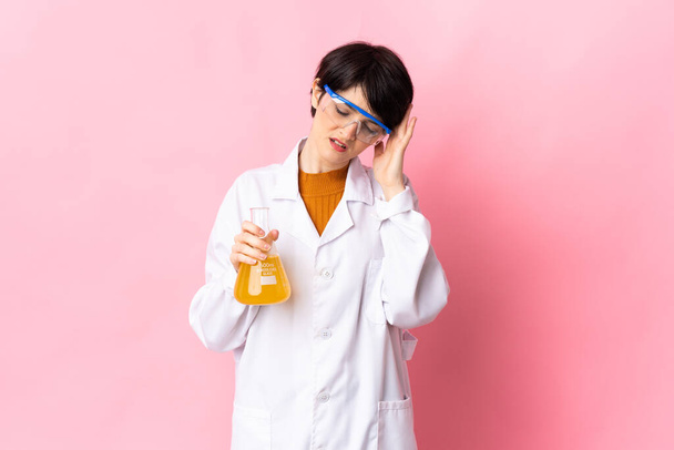 Junge Wissenschaftlerin isoliert auf rosa Hintergrund mit Kopfschmerzen - Foto, Bild