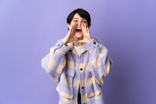 Woman with short hair isolated on purple background shouting and announcing something - Photo, Image