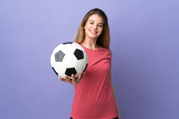 Jonge vrouw met boodschappentas geïsoleerd op paarse achtergrond met voetbal - Foto, afbeelding