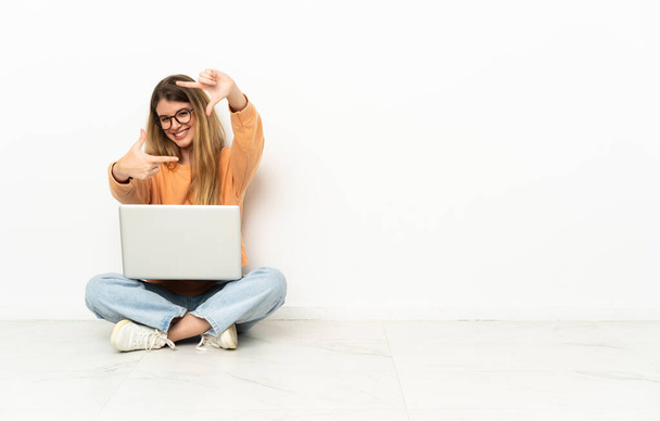 Jonge vrouw met een laptop op de vloer gericht op het gezicht. Framing symbool - Foto, afbeelding