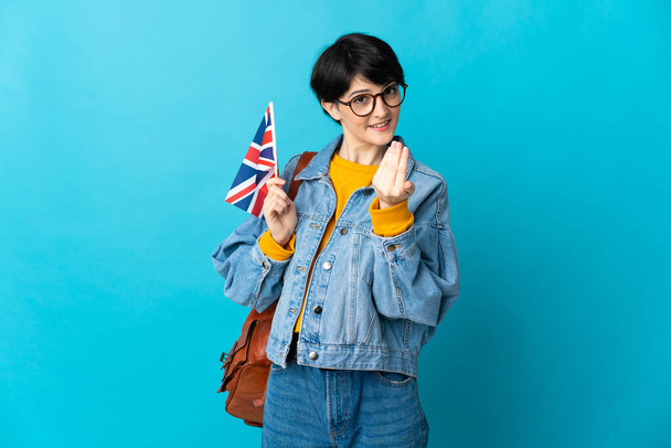 Woman holding an United Kingdom flag over isolated background inviting to come with hand. Happy that you came - Фото, изображение