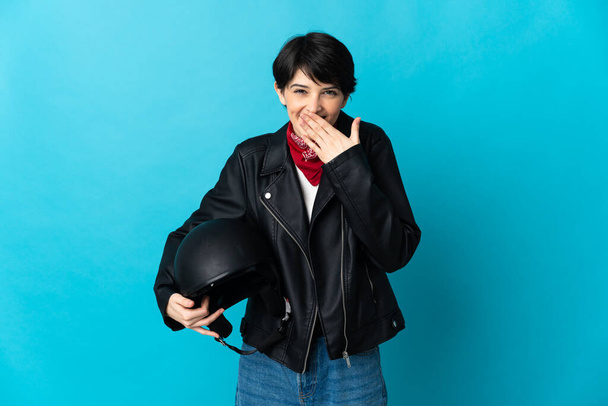 Woman holding a motorcycle helmet over isolated background happy and smiling covering mouth with hand - Photo, Image