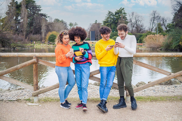 Gruppo di amici multietnici millennials utilizzando i telefoni cellulari dipendenti dalle tendenze tecnologiche che seguono e chattano utilizzando emoji ed emoticon - Foto, immagini