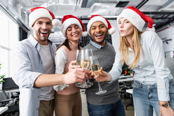 Multiethnic businesspeople smiling while clinking with champagne during new year in office  - Foto, imagen