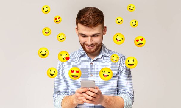 Ευτυχισμένος νεαρός άνδρας που στέλνει μηνύματα στο κινητό του - Φωτογραφία, εικόνα