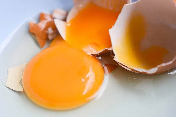 σπασμένο κρόκο αυγού στο μπολ, φρέσκα αυγά κοτόπουλου  - Φωτογραφία, εικόνα