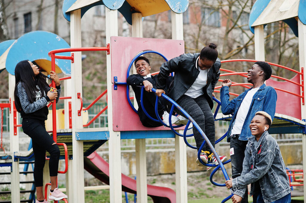 Young millennials african friends on playground, slide and swing. Happy black people having fun together. Generation Z friendship concept. - 写真・画像