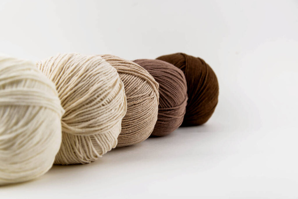 Boules de fil pour tricoter des fleurs brunes sur fond blanc. - Photo, image