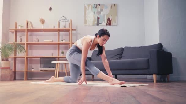 Barefoot sportswoman warming up on fitness mat at home  - Záběry, video