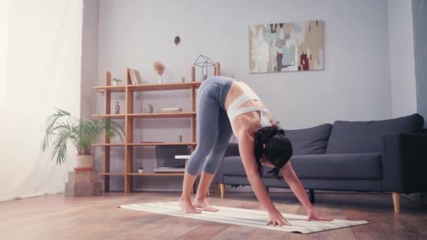 Brunette sportswoman practicing yoga on fitness mat at home  - Filmati, video