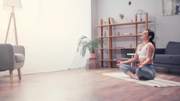 Jovem mulher meditando em lótus posar em casa  - Filmagem, Vídeo