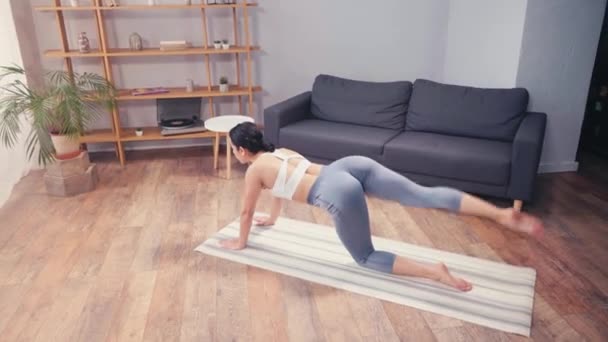 Joven deportista haciendo ejercicio en las nalgas en la alfombra de fitness en casa - Metraje, vídeo
