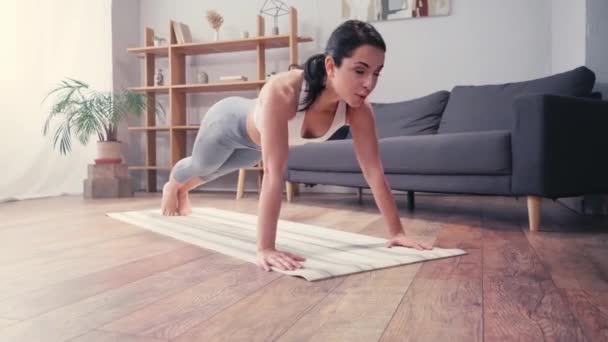 Young sportswoman doing push ups on fitness mat at home  - Footage, Video