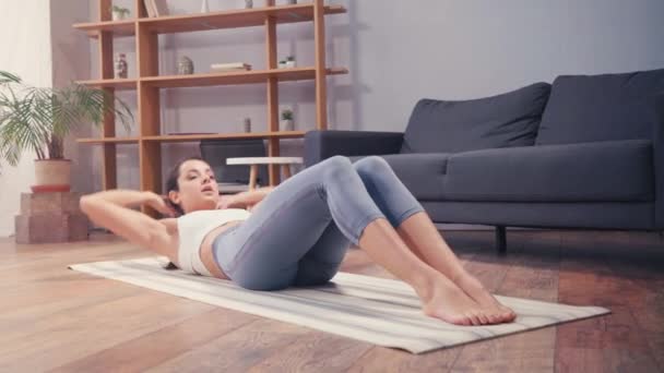 Brunette sportswoman doing abs while training on fitness mat  - Filmati, video