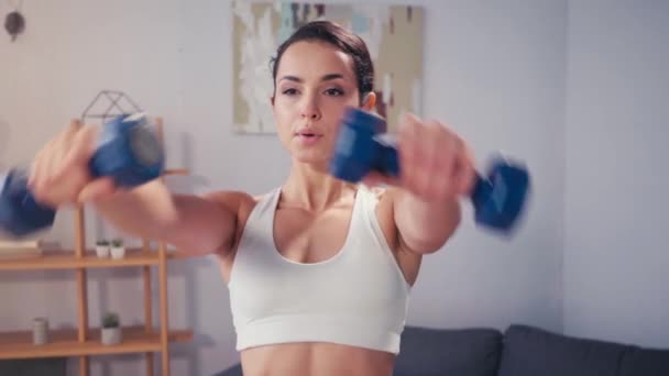 Young sportswoman training with dumbbells in living room  - Footage, Video