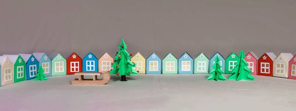Календарь пришествий Оригами. Миниатюра с елкой и бумажными домами. Изолированная на сером фоне, она занимается рукоделием с детьми - Фото, изображение