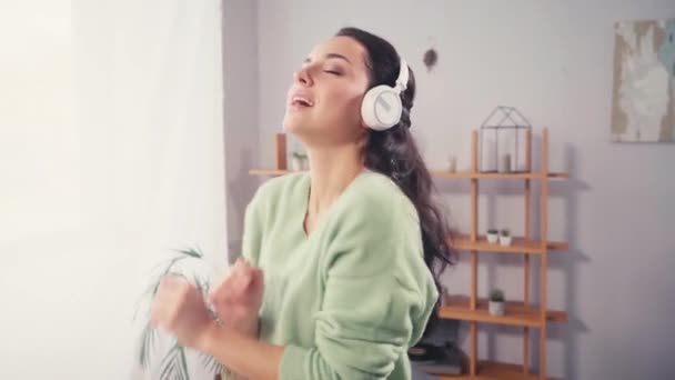 Junge Frau mit Kopfhörern tanzt zu Hause  - Filmmaterial, Video