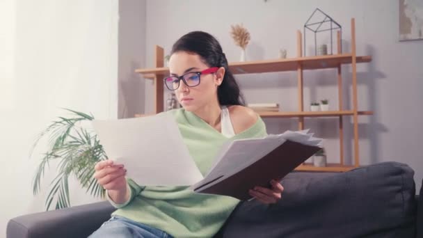 Student mit Brille schaut zu Hause auf Zeitungen  - Filmmaterial, Video