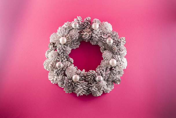 A Christmas wreath with white cones on a pink background - Photo, Image