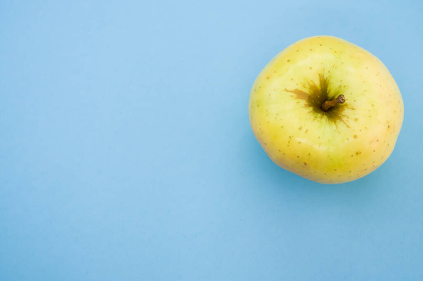 A top view of yellow apple isolated on light blue background - Zdjęcie, obraz