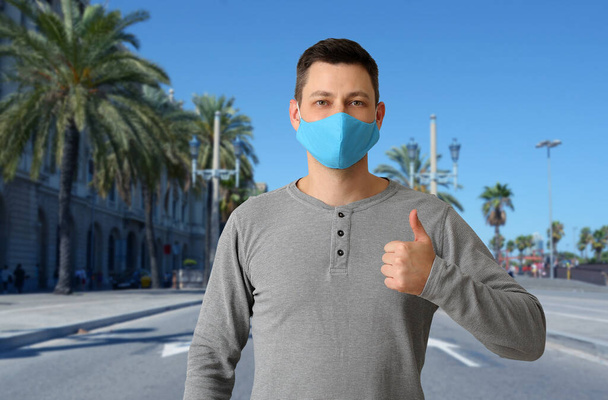 Mannelijke toerist met beschermend masker in tropisch resort. Concept van reizen tijdens een coronavirusepidemie - Foto, afbeelding