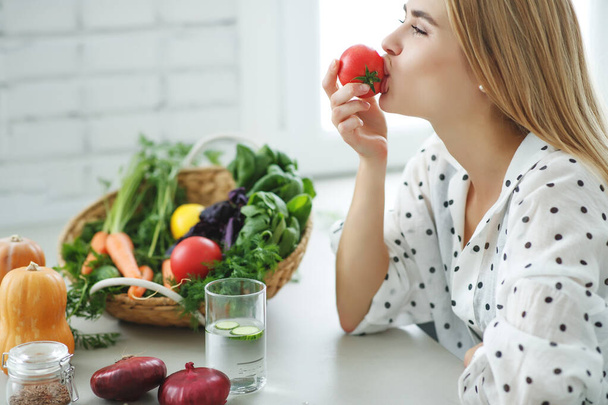 Beautiful young woman eating vegetables in the kitchen. Healthy food. Vegan salad. Diet. Diet concept. Healthy lifestyle. Cook at home. - 写真・画像