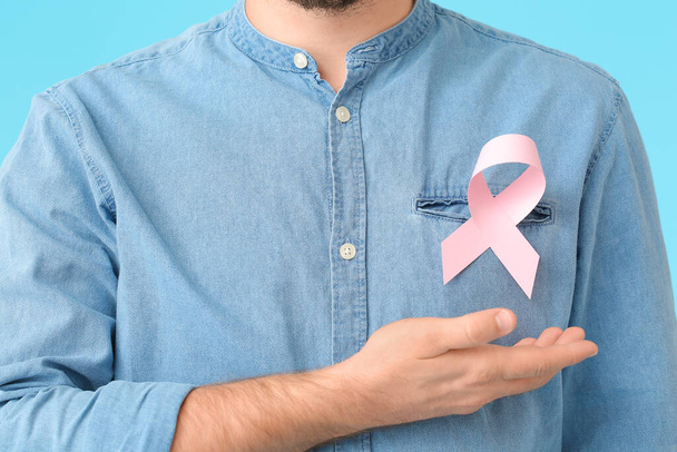 Hombre con cinta rosa sobre fondo de color, primer plano. Concepto de conciencia sobre el cáncer de mama - Foto, Imagen