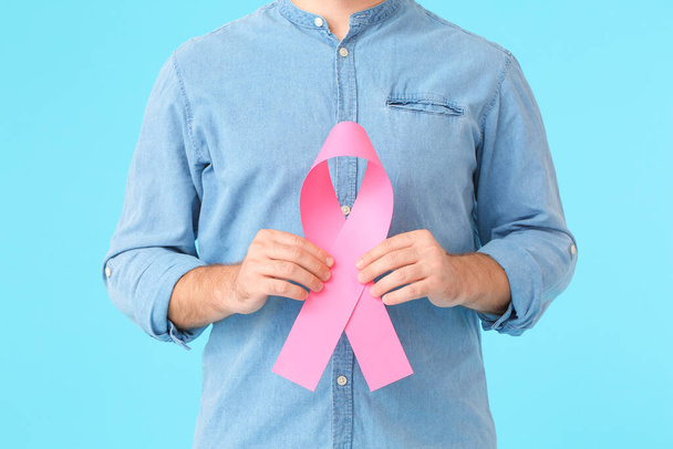 Άνδρας με ροζ κορδέλα στο φόντο χρώμα. Έννοια ευαισθητοποίησης του καρκίνου του μαστού - Φωτογραφία, εικόνα
