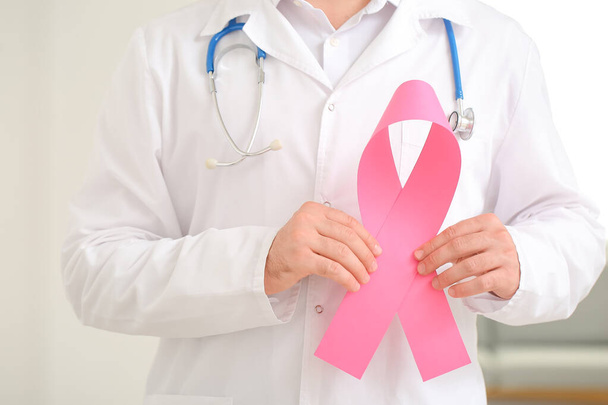 Doctor with pink ribbon in clinic, closeup. Breast cancer awareness concept - Photo, Image