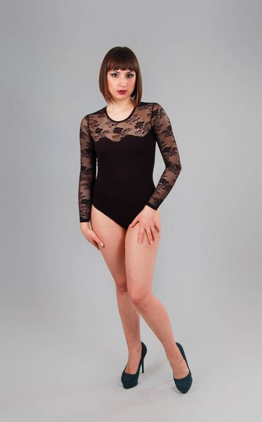 Pretty leggy natural woman in black bodysuit in studio. Isolated background - Photo, Image