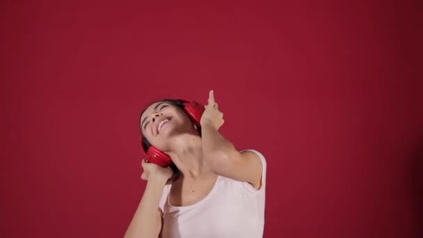 Jonge vrouw met koptelefoon luisteren naar muziek op kleur achtergrond - Video