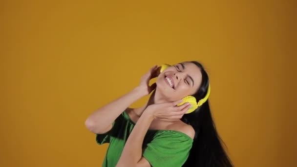 Mujer joven con auriculares escuchando música sobre fondo de color - Metraje, vídeo