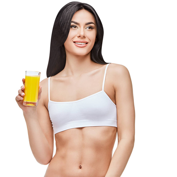 sporty woman over gray background holding glass of orange juice - Фото, изображение