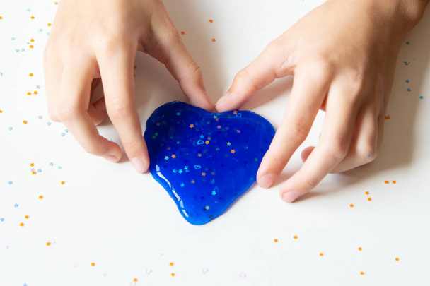 Children's hands make a blue slime on a white background. Close-up. - Photo, Image