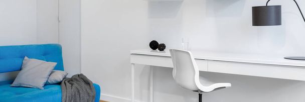Panorama of simple and modern student room with white walls, chair and desk and blue couch  - Foto, Imagen