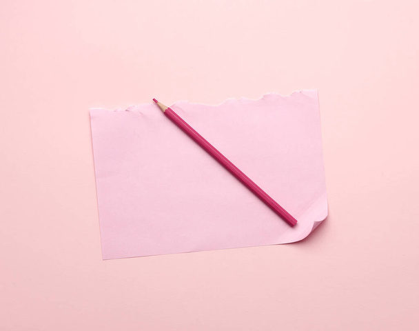 λευκό ροζ σχισμένο φύλλο χαρτιού από ένα σημειωματάριο και ένα ξύλινο μολύβι, πάνω όψη - Φωτογραφία, εικόνα
