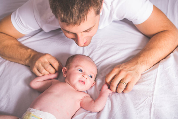 Young father and newborn baby girl on bed at home - Photo, Image