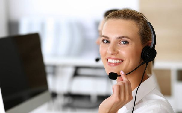 Call center. Happy and excited business woman using headset while consulting clients online. Customer service office or telemarketing department. Smiling group of operators at work - Фото, зображення