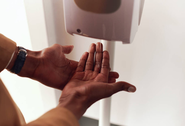 Primo piano dell'uomo d'affari che utilizza il disinfettante per le mani nell'ufficio moderno durante la pandemia sanitaria - Foto, immagini
