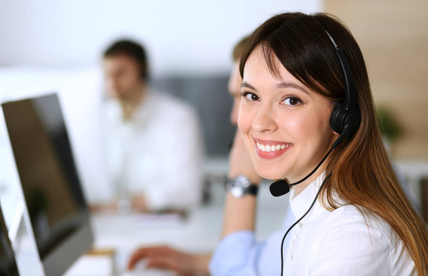 Call center. Group of diverse operators at work. Focus on beautiful asian woman in headset at customer service office. Business concept - 写真・画像