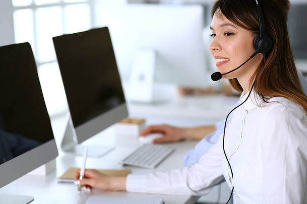 Call center. Group of diverse operators at work. Focus on beautiful asian woman in headset at customer service office. Business concept - Foto, Imagen