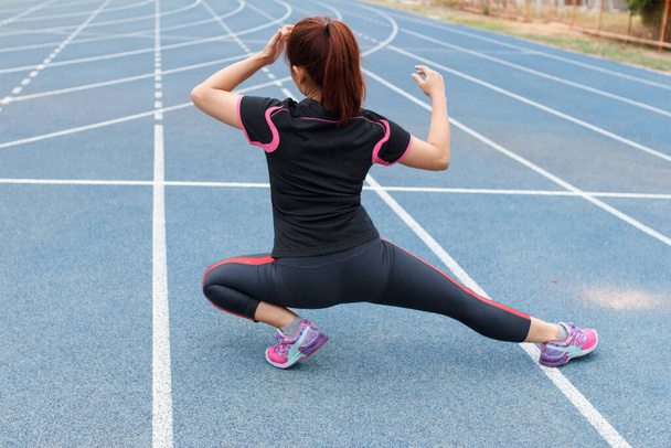 Koşmadan önce bacaklarını esneten genç kadın koşucu - egzersiz konsepti - Fotoğraf, Görsel