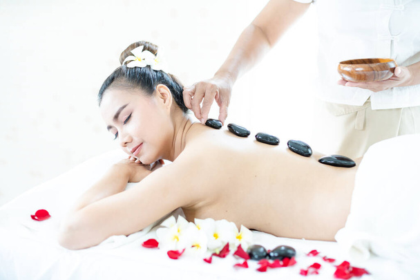 Una masajista de spa está colocando una piedra caliente en una mujer asiática. Acostado en un relajante spa de masajes. - Foto, imagen