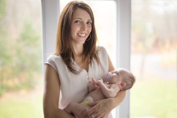 happy family mother with newborn baby in front of window - Photo, image