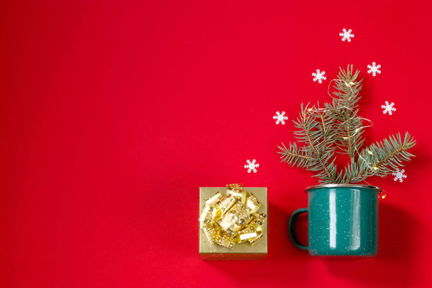Neujahrskarte. Goldene Geschenkschachtel, Christbaumschmuck mit Schneeflocken und Heißgetränk mit Marshmallows auf rotem Hintergrund. Kopierraum - Foto, Bild