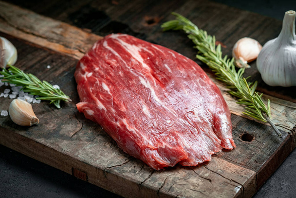 Raw flank beef steak and ingredients for cooking on a wooden Board, close up - Fotografie, Obrázek