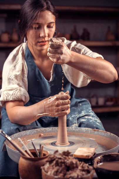 Encantadora joven maestra muestra cómo trabajar con la arcilla y la rueda de cerámica. Concepto para mujer en freelance, negocios, hobby. - Foto, Imagen