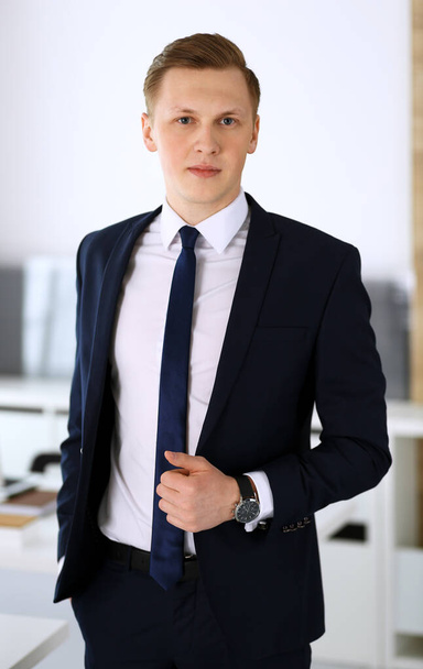 Cheerful businessman standing and looking at camera in office. Headshot of young and successful entrepreneur. Business concept - Фото, зображення