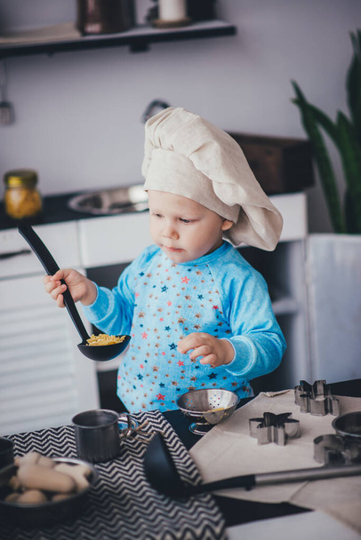 Gyerek fiú séf kalapban és merőkanál a konyhában - Fotó, kép