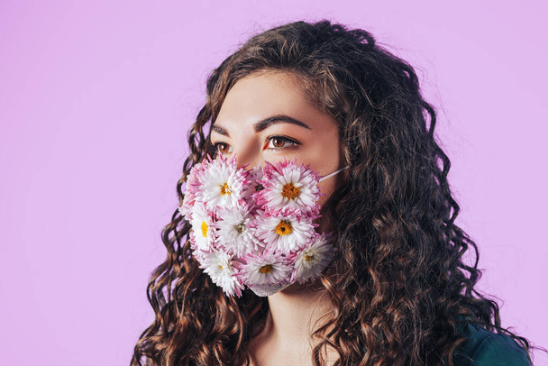 Młoda piękna kobieta w masce ochronnej kwitnących kwiatów na różowym tle. Oddychaj świeżym powietrzem. Zanieczyszczone powietrze. - Zdjęcie, obraz